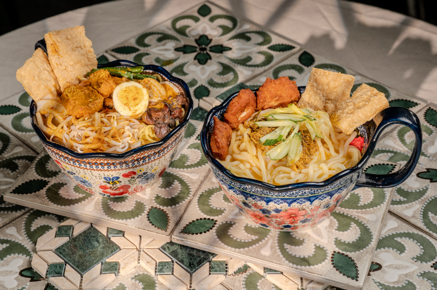 Two curry noodle bowls on heritage tiles