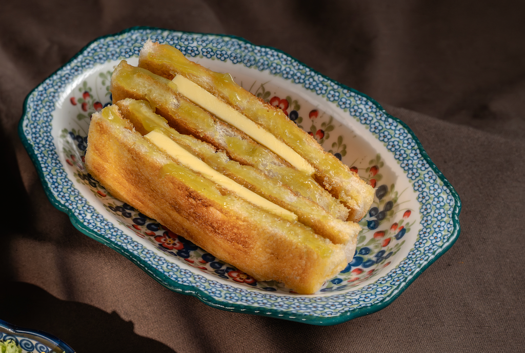 Charcoal-grilled kaya and butter roti bakar on a floral plate
